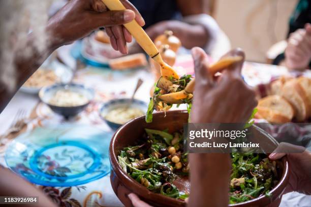 first person view of a woman serving salad at a vegan birthday lunch party - chick pea salad stock pictures, royalty-free photos & images