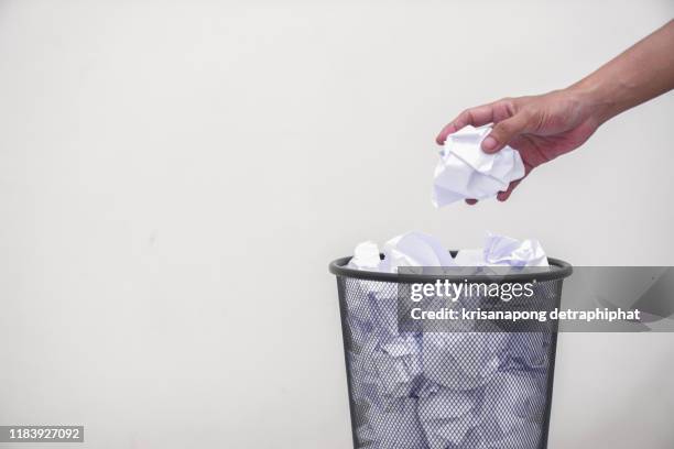 man's hand throwing crumpled paper in basket - crumpled paper ball stock-fotos und bilder