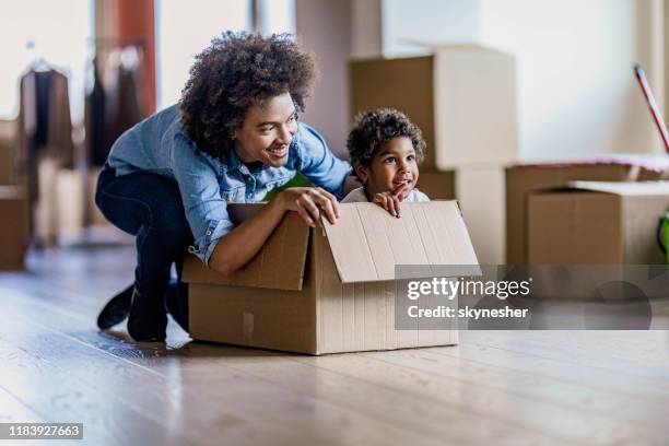 happy single black mother having fun with her daughter in carton box at new apartment. - on the move imagens e fotografias de stock