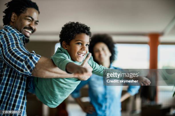 feliz chico afroamericano divirtiéndose con su padre en casa. - eventos de la vida fotografías e imágenes de stock