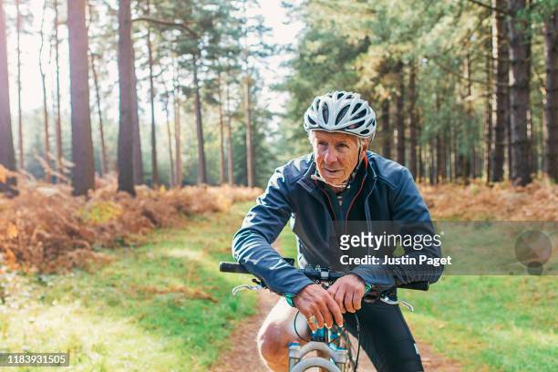 senior male on bike in forest - old man bicycle stock-fotos und bilder