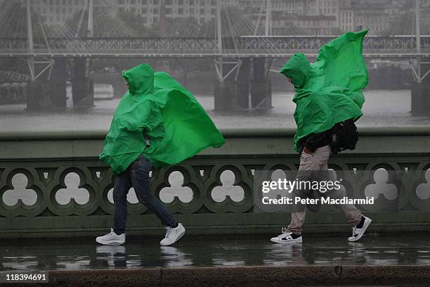 Tourists wearing green ponchos struggle in wet and windy conditions on Westminster Bridge on July 7, 2011 in London, England. Parts of the United...