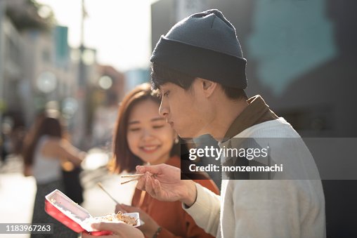 Young couple eating take-out food on street Young couple eating take-out food on street