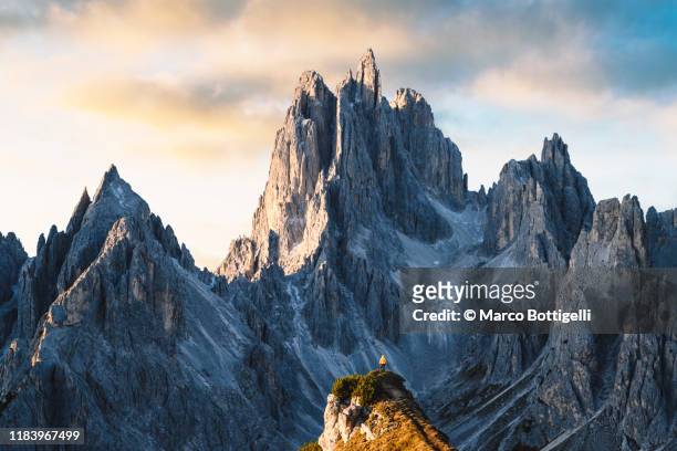 one person standing in front of sharp dolomites peaks, italy - imponente fotografías e imágenes de stock