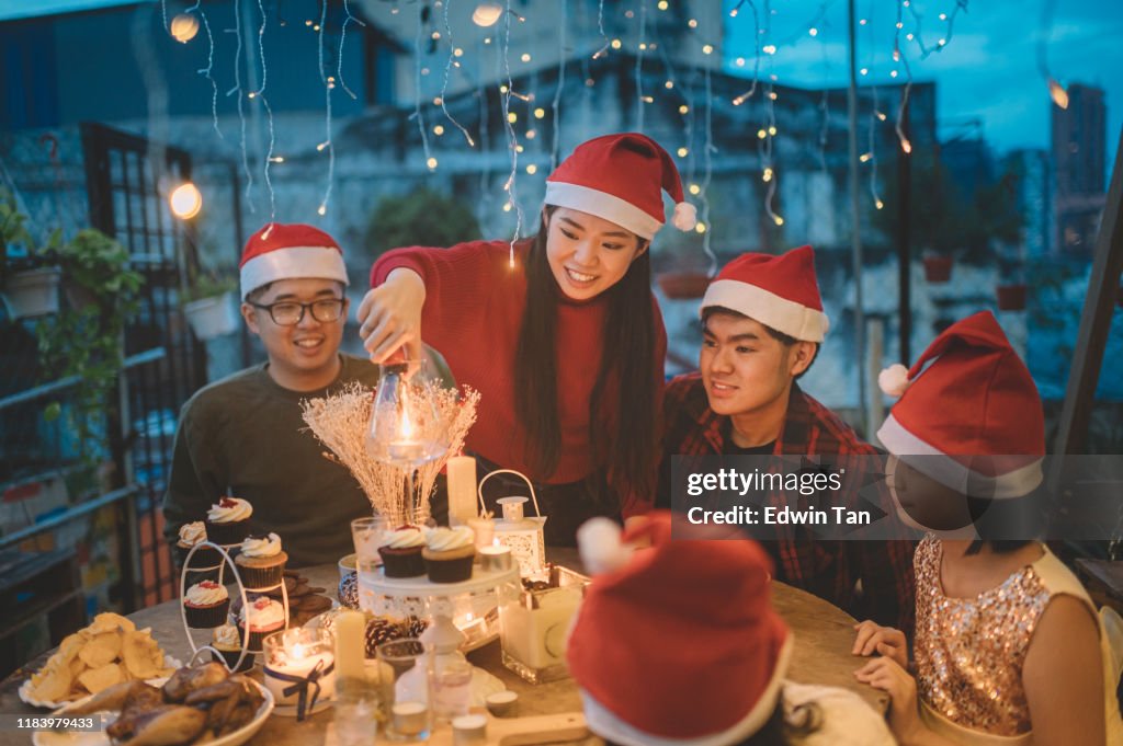An asian chinese siblings and friends celebrating christmas dinner at front yard of house lighting up candle and setting up table