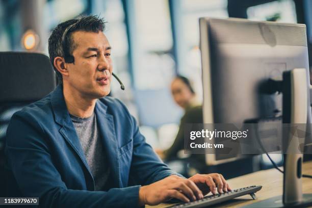 uomo asiatico maturo che lavora in un call center - call centre asian foto e immagini stock