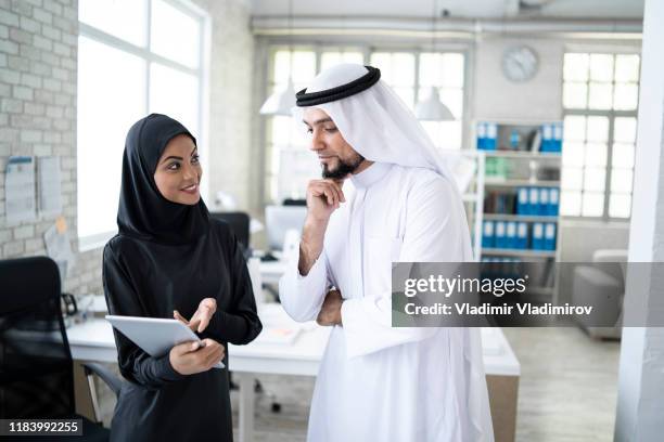 female assistant discussing with arab businessman in modern office - ksa people stock pictures, royalty-free photos & images