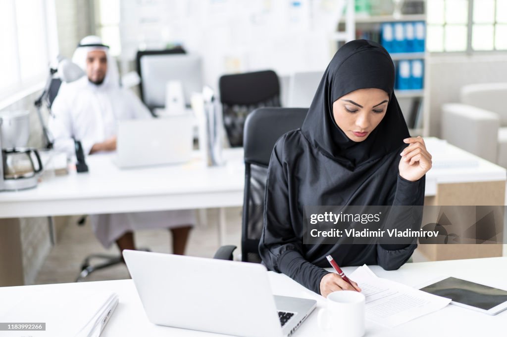 Arab businesswoman working in modern office, writing