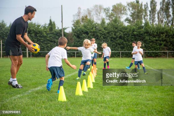 junge fußballer üben laufübungen während des trainings - football training stock-fotos und bilder
