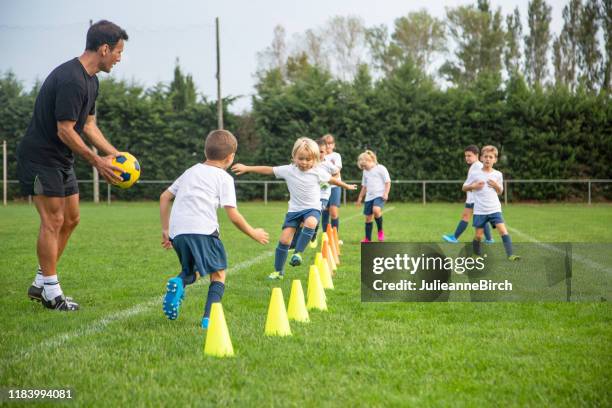 jóvenes futbolistas practicando ejercicios de carrera durante la práctica - practicing fotografías e imágenes de stock