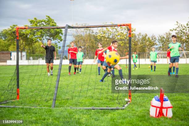 kick getting past footballer for scoring goal - junior level stock pictures, royalty-free photos & images