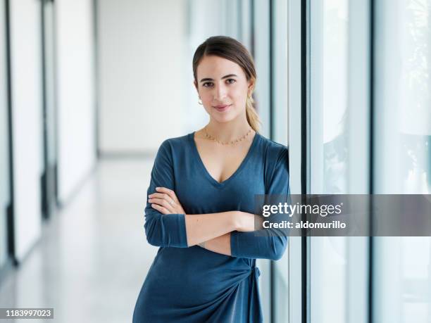 young latin woman standing with arms crossed and  looking at camera - medium shot stock pictures, royalty-free photos & images