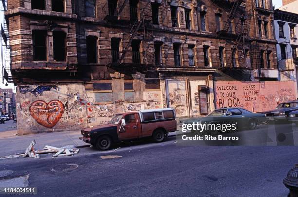 View of the graffiti-covered facade of an empty building in the Lower East Side neighborhood, New York, New York, 1990. Text at right reads 'Welcome...