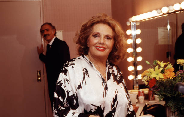 Portrait of Portuguese Fado singer Amalia Rodrigues as she sits backstage at Town Hall, New York, New York, November 2, 1990. Behind her is record...