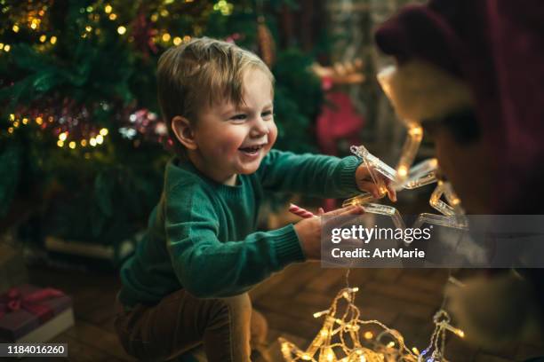 クリスマスツリーの近くでライトの装飾で遊ぶ屋内の家族 - christmas family tree ストックフォトと画像