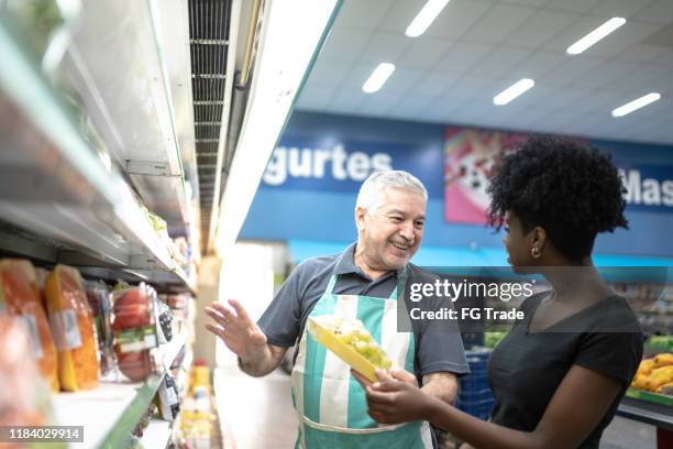 supermarkt-mitarbeiter hilft einem kunden bei der auswahl von gemüse - supermarket help stock-fotos und bilder