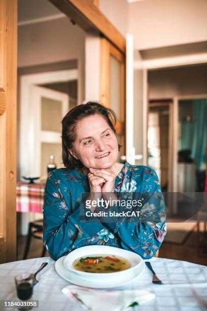 vertikales porträt der seniorin am küchentisch - slawische kultur stock-fotos und bilder