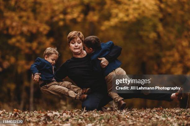 action shot of mother falling over holding fraternal twin toddlers in suit jackets - kid mess child stock-fotos und bilder