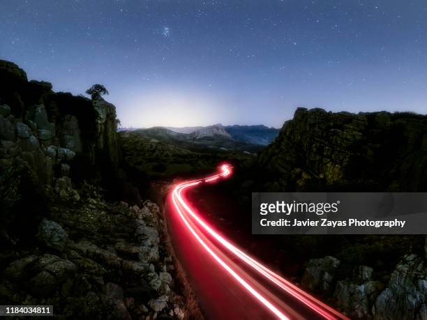 lights of vehicle circulating along a road of mountain with curves at night - winding road night stock pictures, royalty-free photos & images
