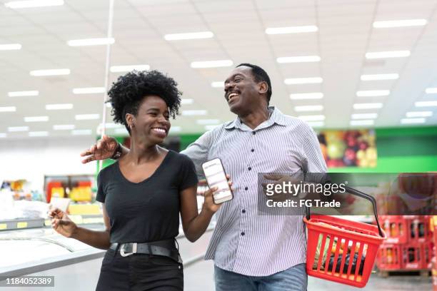 father and daughter dancing and having fun in supermarket - convenience basket stock pictures, royalty-free photos & images