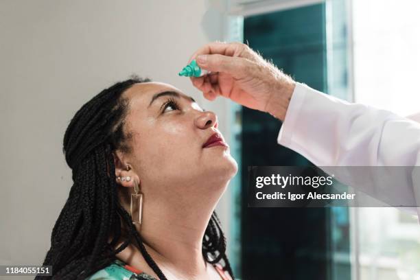 dripping eye drops during consultation with an ophthalmologist - eye drop stock pictures, royalty-free photos & images