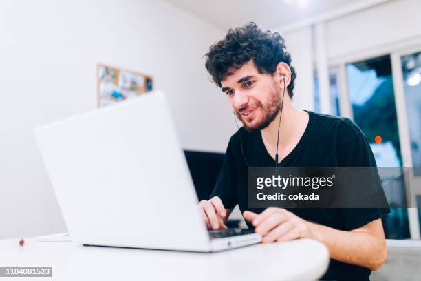 gelukkig jonge man met behulp van laptop werken thuis - pardo brazilian stockfoto's en -beelden