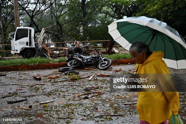 Woman walks past vehicle wreckage at the scene of a blast targeting a police station in Santander de Quilichao, Cauca department, on November 23,...
