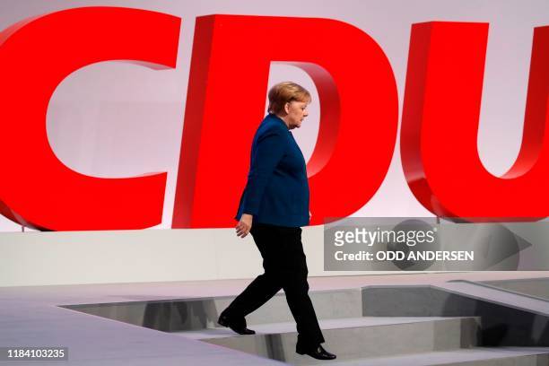 German Chancellor Angela Merkel walks past her party's logo at the end of a party congress of Germany's Christian Democratic Union on November 23,...