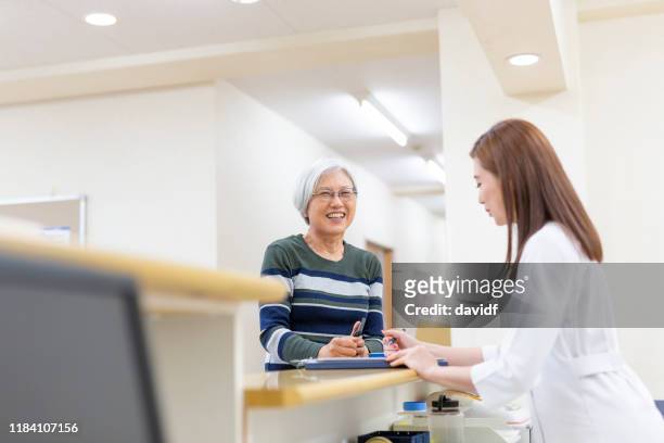 patienteneinchecken in der krankenstation - schwesterntisch stock-fotos und bilder