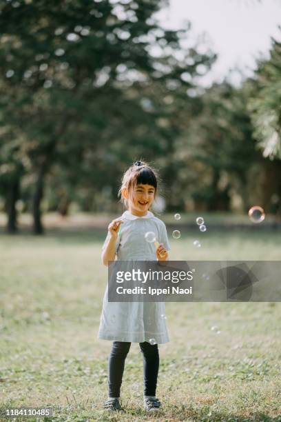 cute young girl blowing bubbles in park - bubble ponytail stock pictures, royalty-free photos & images