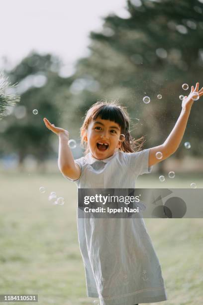 cute young girl playing with bubbles in park - bubble ponytail stock pictures, royalty-free photos & images