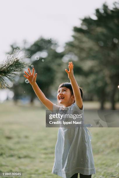 cute young girl playing with bubbles in park - bubble ponytail stock pictures, royalty-free photos & images