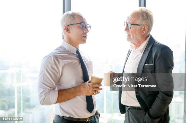 business people sharing great ideas concepts. senior business man holding cups of coffee and discussing something while sitting together near the window. - share office stock pictures, royalty-free photos & images