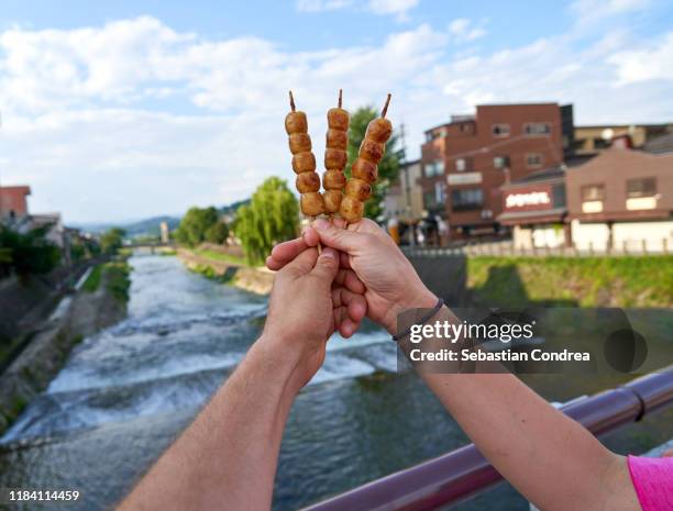 two tourist showing japanese street food dango rice dumpling sweet dish, asanogawa bridge, kyoto japan travel, jr route. - nishiki market fotografías e imágenes de stock