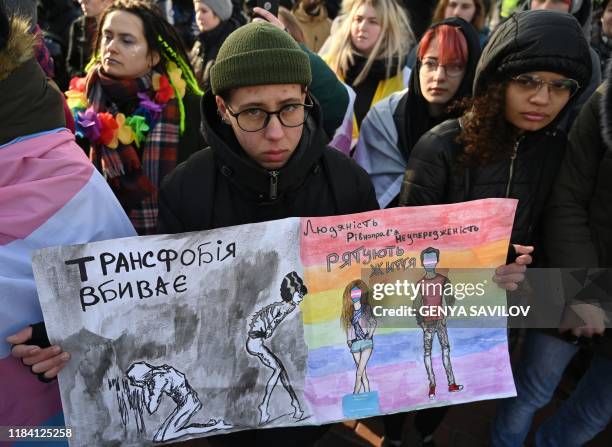 Participants hold drawings reading 'Transphobia kills, humanity saves' during an anti-transphobia rally in Kiev, on November 23, 2019. - Dozen of...