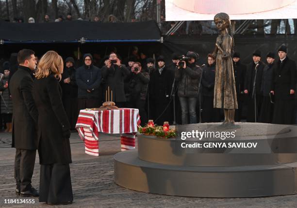 Ukrainian President Volodymyr Zelensky and his wife Olena pay their respects as they take part in a commemoration ceremony at a monument of victims...