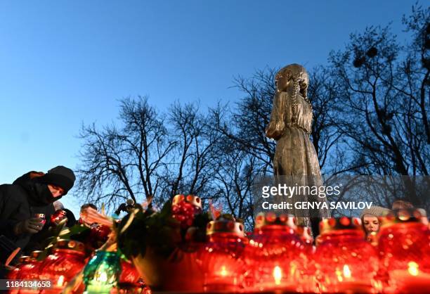 People lay symbolic sheaves of wheat and light candles during a commemoration ceremony at a monument to victims of the Holodomor famine of 1932-33 in...