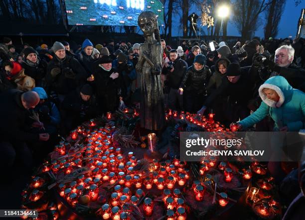 People lay symbolic sheaves of wheat and light candles during a commemoration ceremony at a monument of victims of the Holodomor famine of 1932-33 in...