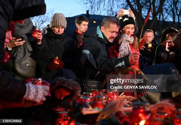 People lay symbolic sheaves of wheat and light candles during a commemoration ceremony at a monument to victims of the Holodomor famine of 1932-33 in...