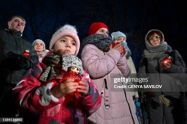 People hold candles during a commemoration ceremony at a monument to victims of the Holodomor famine of 1932-33 in Kiev on November 23, 2019. -...