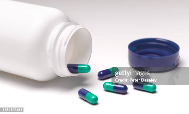 open pill bottle with pills spilling out - antibiótico fotografías e imágenes de stock