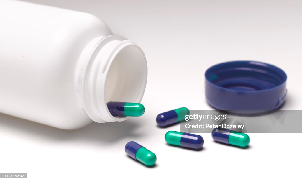 Open pill bottle with pills spilling out