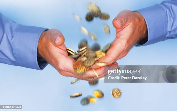 gold coins falling through business man's hands - sorte imagens e fotografias de stock