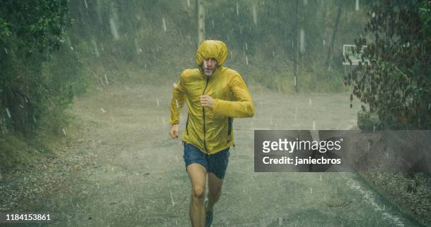 atletische man joggen in extreme weersomstandigheden. hagel en regen - rainy day stockfoto's en -beelden
