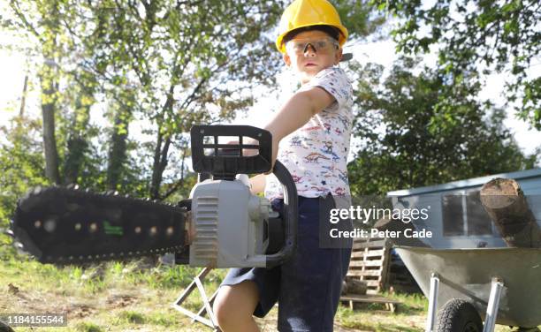 child holding chainsaw - boy in hard hat stock pictures, royalty-free photos & images