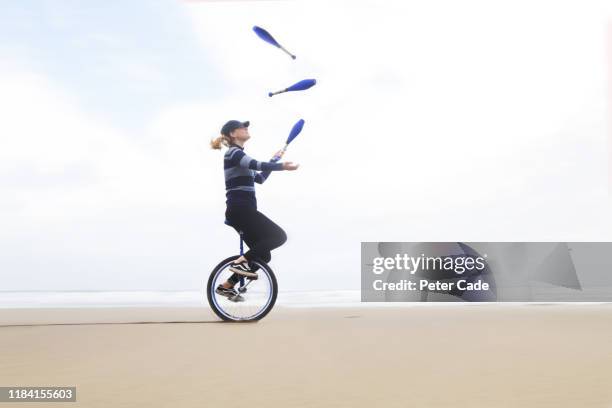 woman juggling on a unicycle - giocoliere foto e immagini stock