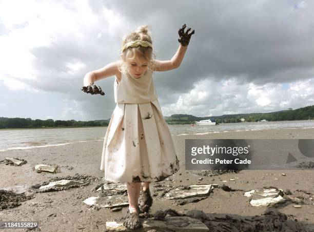 young girl jumping stepping stones along river bed - girls in wet dresses stock-fotos und bilder
