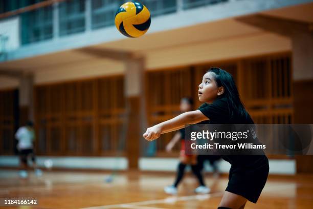 Young girl playing volleyball at a team practice in a school gym