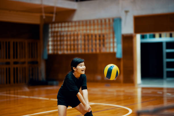 young girl playing volleyball at a team practice in a school gym - girls volleyball stock pictures, royalty-free photos & images