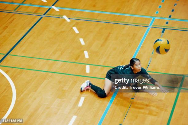 young girl playing volleyball at a team practice in a school gym - zaalvolleybal stockfoto's en -beelden